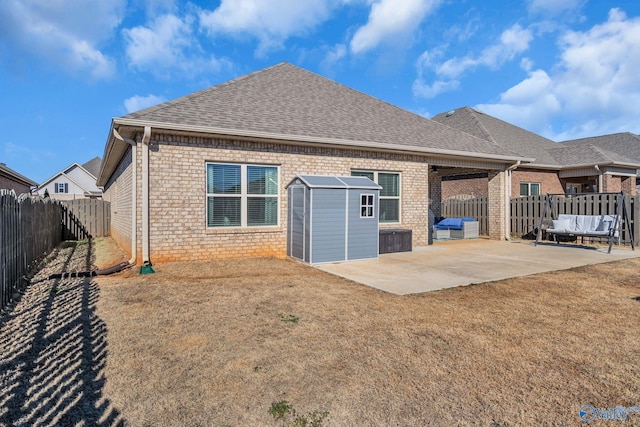 rear view of property with a storage unit, a lawn, and a patio area