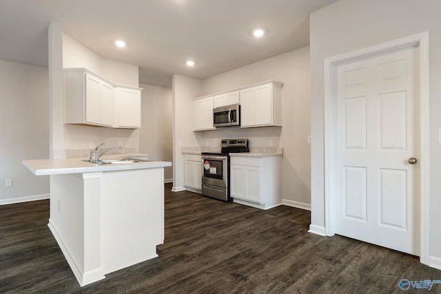 4025 Sherri St SW, Decatur, AL 35603 - kitchen featuring appliances with stainless steel finishes, a peninsula, dark wood-style flooring, white cabinetry, and recessed lighting