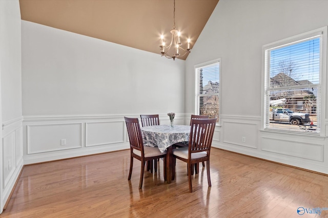 dining space featuring lofted ceiling, a notable chandelier, and light hardwood / wood-style flooring