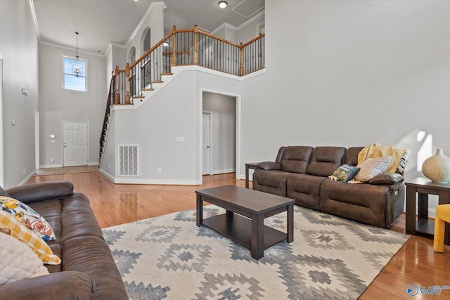 living room featuring ornamental molding, hardwood / wood-style floors, and a high ceiling