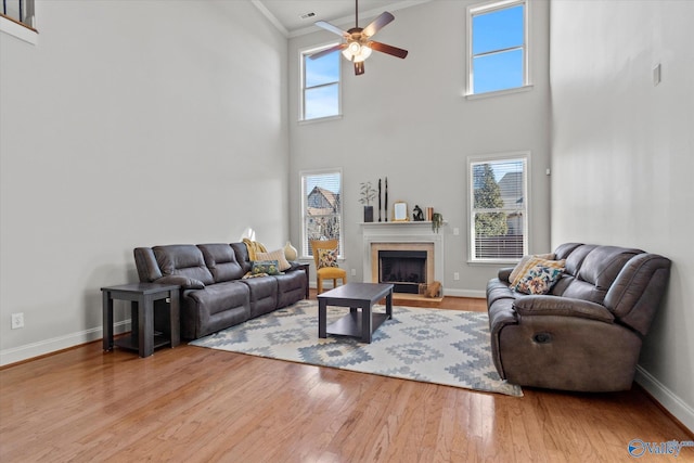 living room featuring hardwood / wood-style flooring, ceiling fan, a high ceiling, and a wealth of natural light