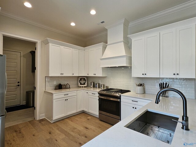 kitchen with white cabinets, custom exhaust hood, gas stove, and light hardwood / wood-style floors