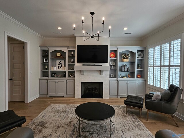 living room with a large fireplace, light hardwood / wood-style floors, a notable chandelier, and ornamental molding