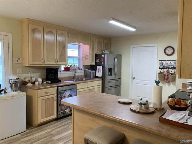 kitchen with sink, light brown cabinetry, a textured ceiling, and appliances with stainless steel finishes