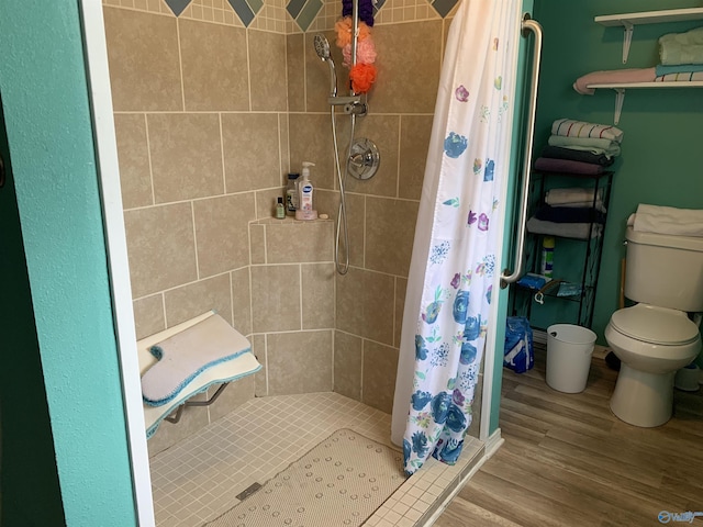 bathroom featuring toilet, a stall shower, and wood finished floors