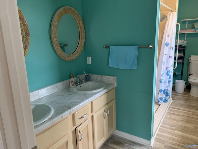 full bathroom featuring toilet, double vanity, wood finished floors, curtained shower, and baseboards