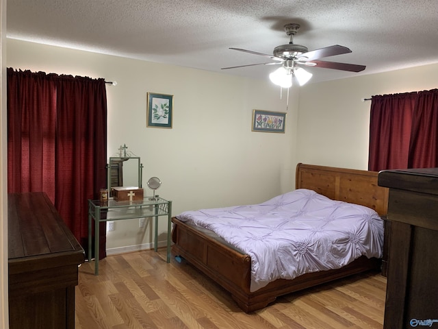 bedroom featuring light wood-type flooring, a textured ceiling, and a ceiling fan
