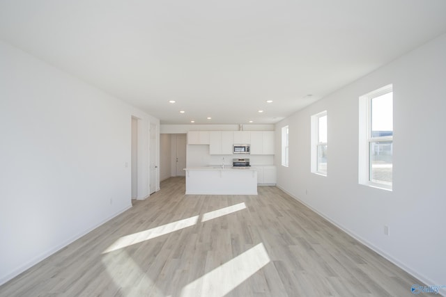 unfurnished living room with sink and light hardwood / wood-style floors