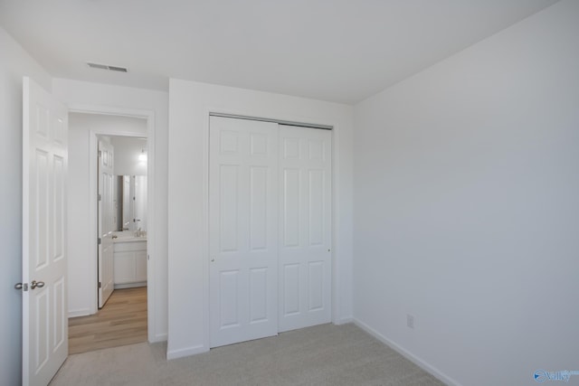 unfurnished bedroom with light carpet and a closet