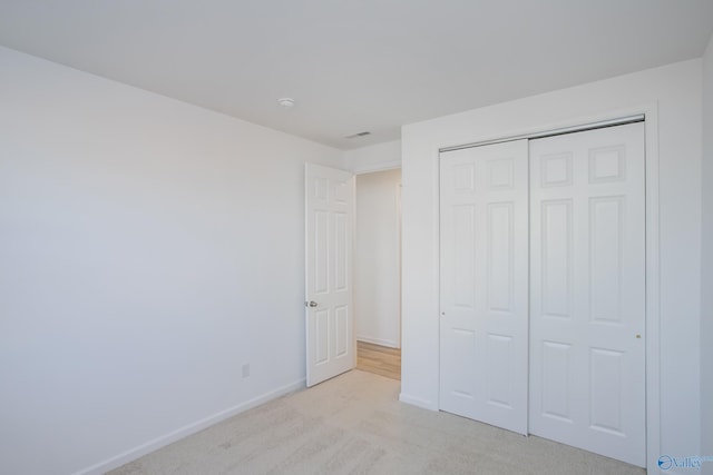 unfurnished bedroom featuring a closet and light colored carpet