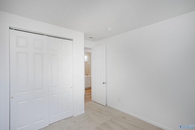 unfurnished bedroom with a closet and light colored carpet