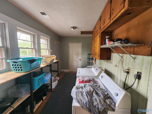 clothes washing area with cabinet space, a textured ceiling, visible vents, and washer and clothes dryer
