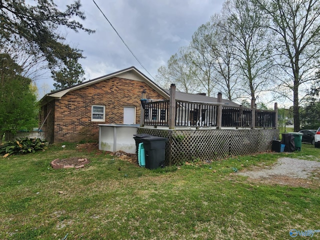rear view of property featuring brick siding, a lawn, an outdoor pool, and a deck