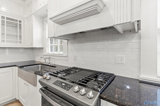 kitchen featuring sink, stainless steel gas range, custom range hood, tasteful backsplash, and white cabinetry