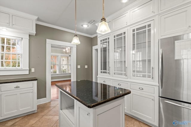 kitchen with stainless steel refrigerator, white cabinetry, light tile patterned floors, and pendant lighting