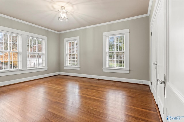 spare room with crown molding, an inviting chandelier, and hardwood / wood-style flooring