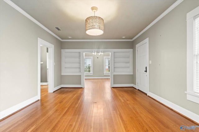 unfurnished living room featuring a chandelier, wood-type flooring, built in shelves, and ornamental molding