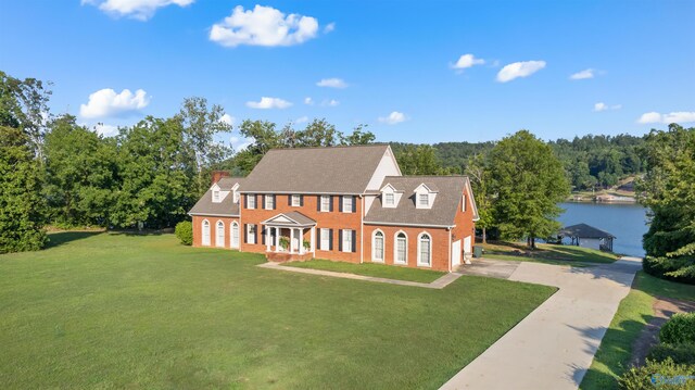 colonial house with a front yard and a water view