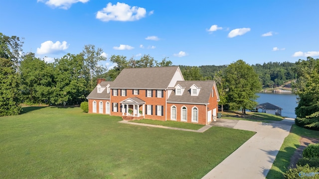 view of front of property featuring a water view, brick siding, concrete driveway, and a front yard