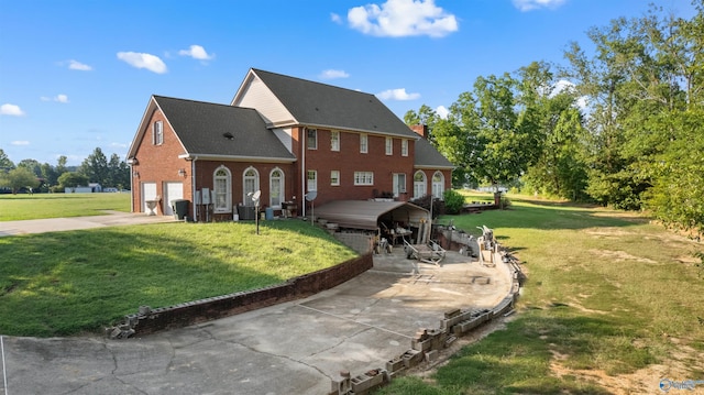 view of front of property with central air condition unit, brick siding, driveway, a front lawn, and a chimney