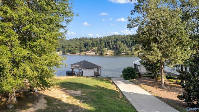 view of dock with a water view, a forest view, and a yard