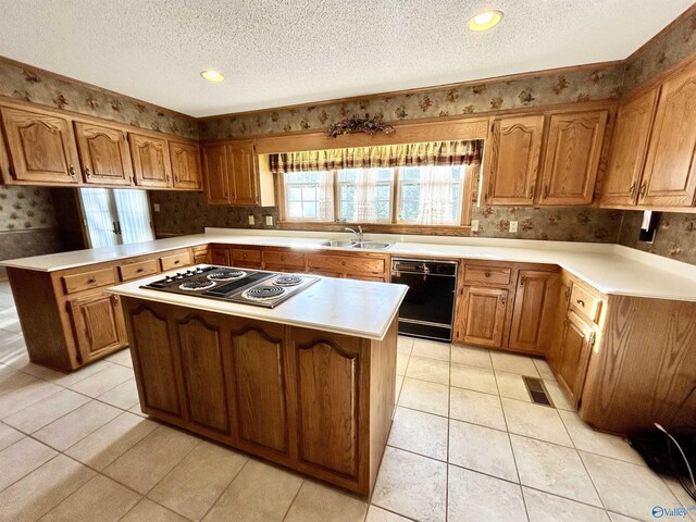 kitchen with a textured ceiling, a kitchen island, light tile patterned floors, stainless steel cooktop, and double oven