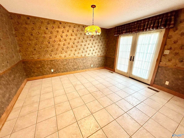 tiled empty room with french doors and a textured ceiling