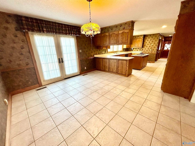 kitchen featuring pendant lighting, light tile patterned floors, kitchen peninsula, and a textured ceiling