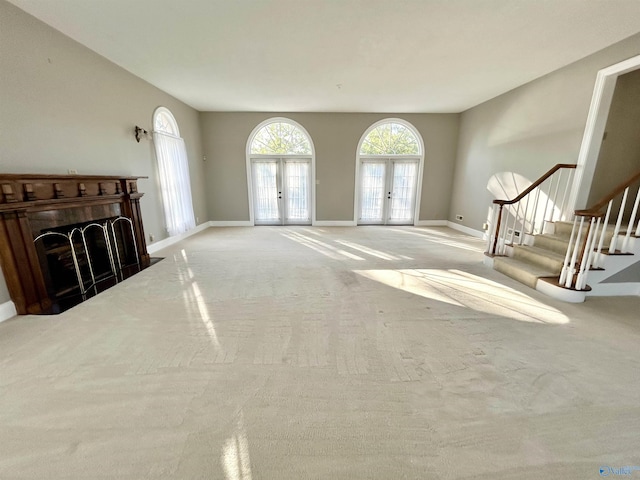 living room featuring a fireplace with flush hearth, french doors, carpet flooring, and stairs