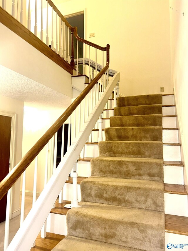 stairs with a textured ceiling and hardwood / wood-style floors