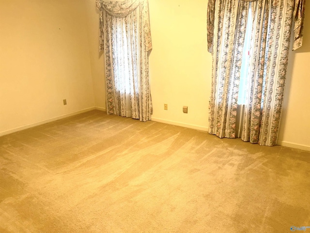 empty room featuring carpet and baseboards