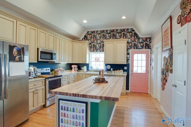 kitchen featuring cream cabinets, a kitchen island, stainless steel appliances, and lofted ceiling