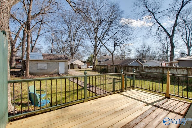 wooden terrace featuring a lawn and an outbuilding