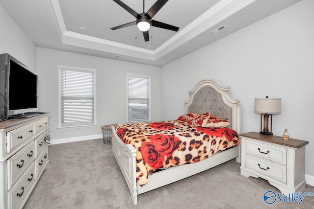 carpeted bedroom with a tray ceiling, ceiling fan, and crown molding