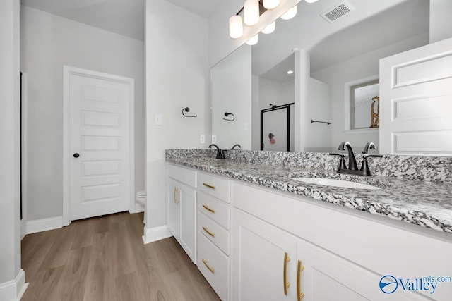 bathroom featuring vanity, hardwood / wood-style flooring, toilet, and walk in shower