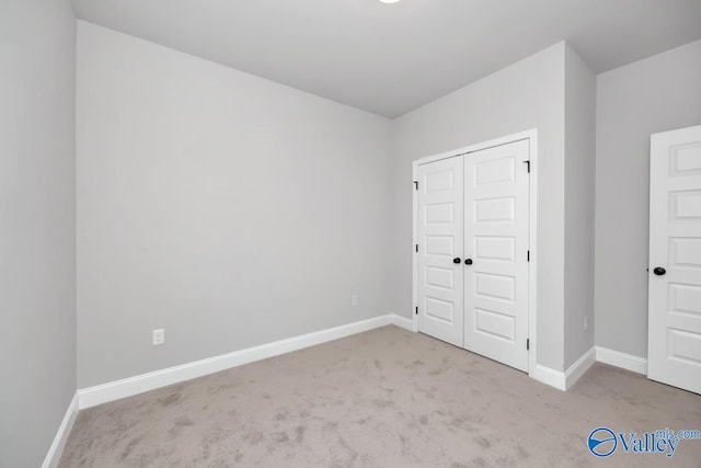 unfurnished bedroom with light carpet and a closet