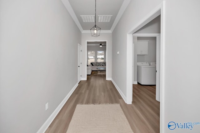 corridor with crown molding, wood-type flooring, and independent washer and dryer