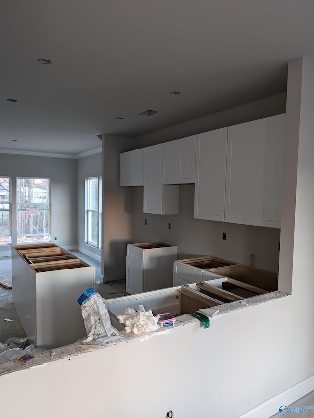 kitchen with white cabinets, fridge, and ornamental molding