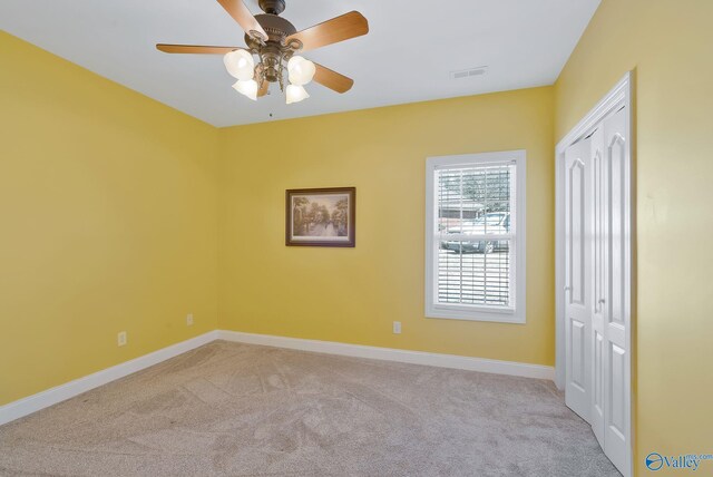 unfurnished bedroom featuring visible vents, a closet, carpet floors, baseboards, and ceiling fan