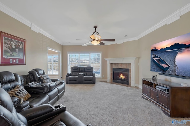 living room with ornamental molding, a tiled fireplace, baseboards, light colored carpet, and ceiling fan