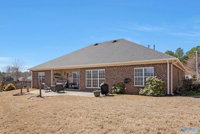 back of property featuring fence, a patio area, brick siding, and a lawn