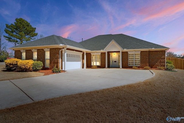 single story home with a garage, brick siding, driveway, and fence