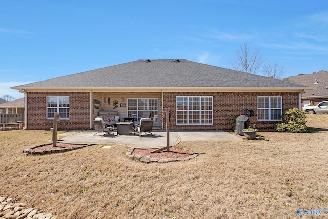 back of property with brick siding, a lawn, a shingled roof, and a patio