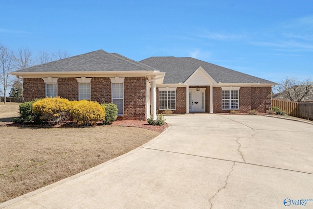 view of front of property with brick siding, a shingled roof, and fence