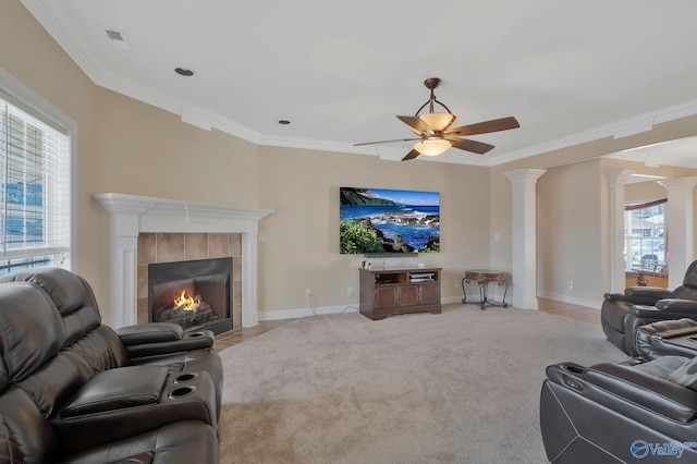 carpeted living area featuring baseboards, ornamental molding, a tiled fireplace, and ornate columns