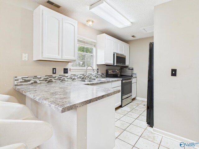 201 Turnbrook Dr SW, Huntsville, AL 35824 - kitchen with stainless steel appliances, a peninsula, white cabinets, a breakfast bar area, and light tile patterned floors