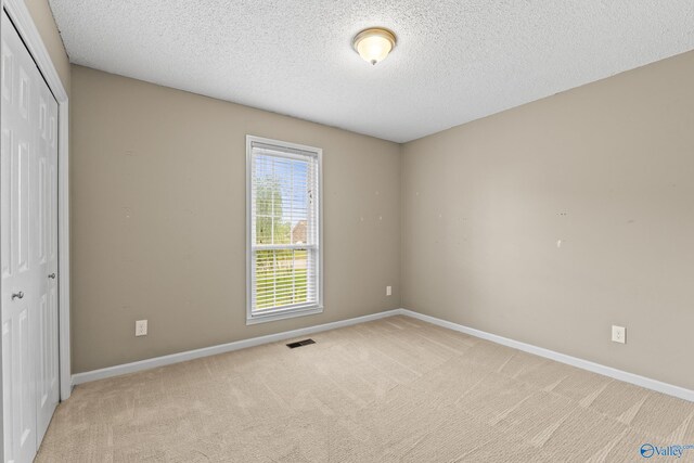 2009 SW Danbury Cir SW, Huntsville, AL 35803 - unfurnished bedroom with a closet, light carpet, baseboards, and a textured ceiling