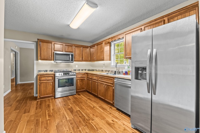 2009 SW Danbury Cir SW, Huntsville, AL 35803 - kitchen featuring appliances with stainless steel finishes, a sink, light countertops, light wood-style floors, and brown cabinetry