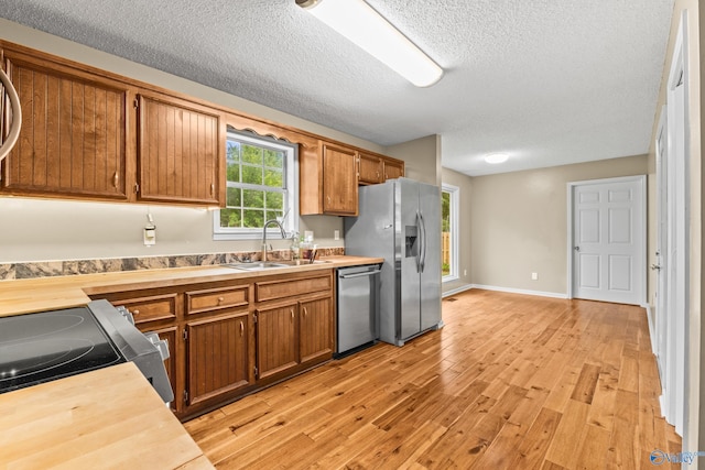 2009 SW Danbury Cir SW, Huntsville, AL 35803 - kitchen featuring stainless steel appliances, a sink, brown cabinets, light wood finished floors, and a textured ceiling