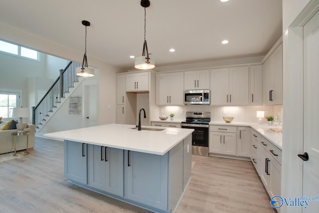 kitchen featuring white cabinetry, decorative backsplash, light wood-type flooring, sink, and appliances with stainless steel finishes